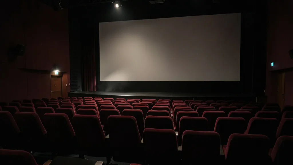 Imagem gerada por IA: Sala de cinema vazia diante de uma tela iluminada.