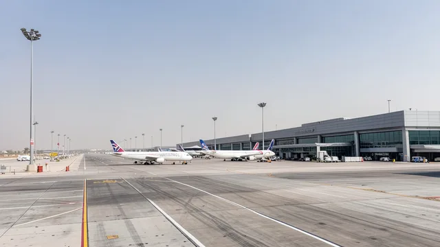 Imagem gerada por IA: Aeronaves estacionadas em uma área de embarque do aeroporto de Riad, com poucas movimentações visíveis.