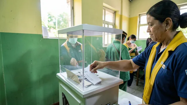 Imagem gerada por IA: Eleitor deposita uma cédula em urna transparente durante votação.