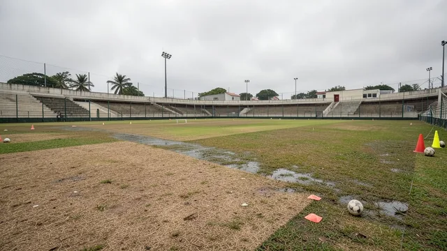 Imagem gerada por IA: Campo de treinamento com áreas de gramado seco e outras visivelmente molhadas.