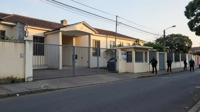 Entrada fechada de um complexo diplomático em Brasília, com guarita e presença policial discreta.
