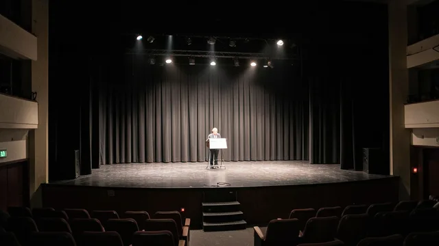 Imagem gerada por IA: Palco vazio de teatro com cortina parcialmente fechada e refletores acesos.