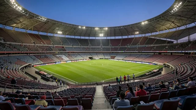 Arquibancadas do Maracanã iluminadas ao entardecer, com visitantes em um tour pelo estádio.