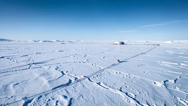 Imagem gerada por IA: Paisagem do Polo Sul com uma estação de pesquisa e a vasta extensão de gelo do observatório IceCube.
