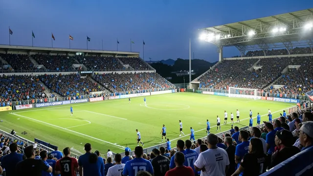 Imagem gerada por IA: Estádio de futebol iluminado antes de uma partida, com jogadores aquecendo e torcedores nas arquibancadas.