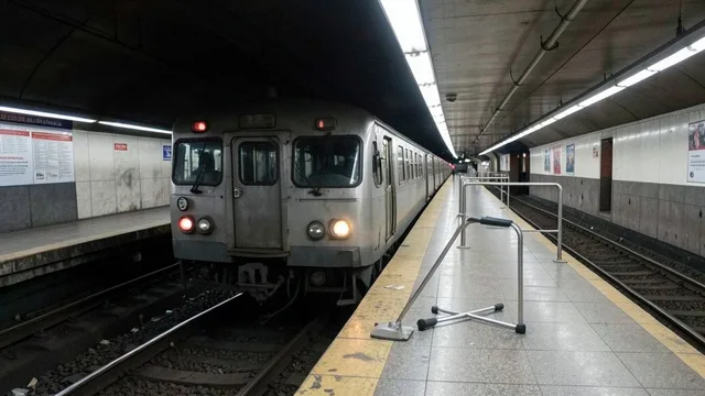 Imagem gerada por IA: Uma muleta metálica perto dos trilhos de uma estação de metrô, com um trem parado ao fundo.