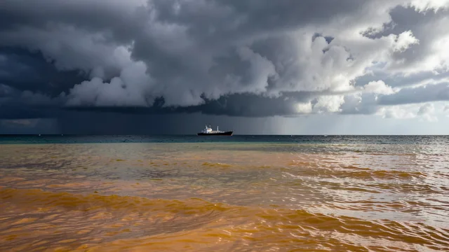 Imagem gerada por IA: Oceano Pacífico equatorial sob nuvens carregadas, com um navio de pesquisa ao longe.