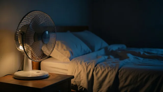 Imagem gerada por IA: Ventilador e copo d’água ao lado da cama em uma cena noturna.