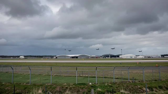 Imagem gerada por IA: Pista e hangares de uma base aérea militar sob céu nublado.