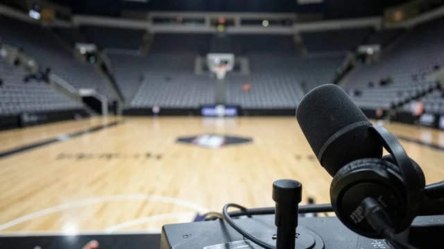 Microfone e fones de transmissão diante de uma quadra de basquete vazia.