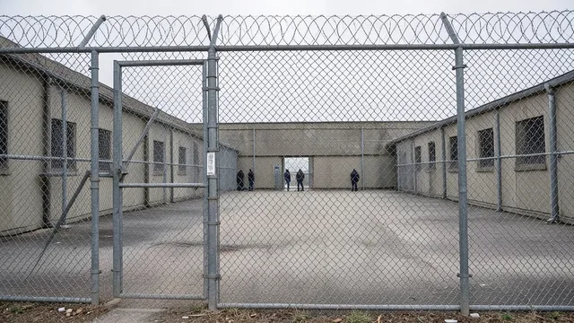Centro de detenção de imigrantes nos Estados Unidos visto por trás de uma cerca.