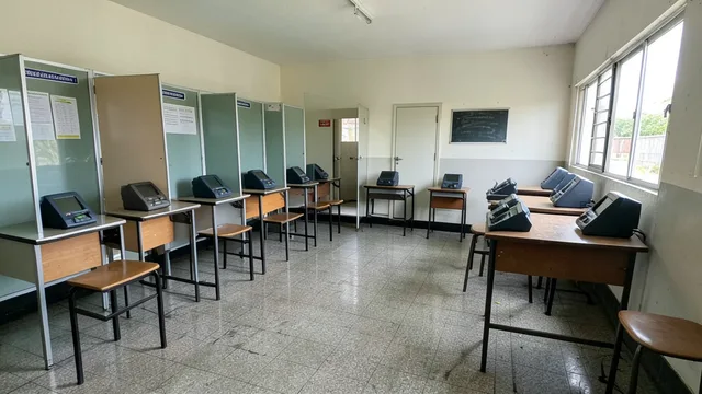 Imagem gerada por IA: Sala de votação vazia, com cabines e urnas eletrônicas organizadas.